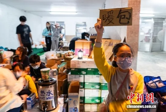 11月27日晚，青少年参与为火灾受影响市民提供热水、暖包等物资帮助。中新社记者 侯宇 摄