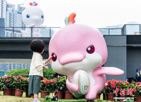 图为一名小女孩在吉祥物“乐融融”雕塑旁玩耍。中新网记者 侯宇 摄